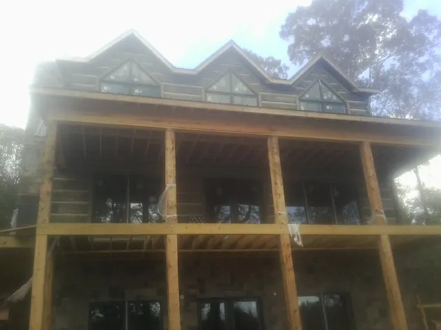 Dormers and porch framing on a large log home under construction — Roof Coating work by our crew in Dumont
