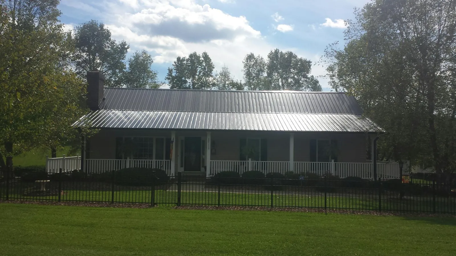 Gray metal roof on a brick ranch with a full width front porch — Gutter Guard Installation work by our crew in Dumont